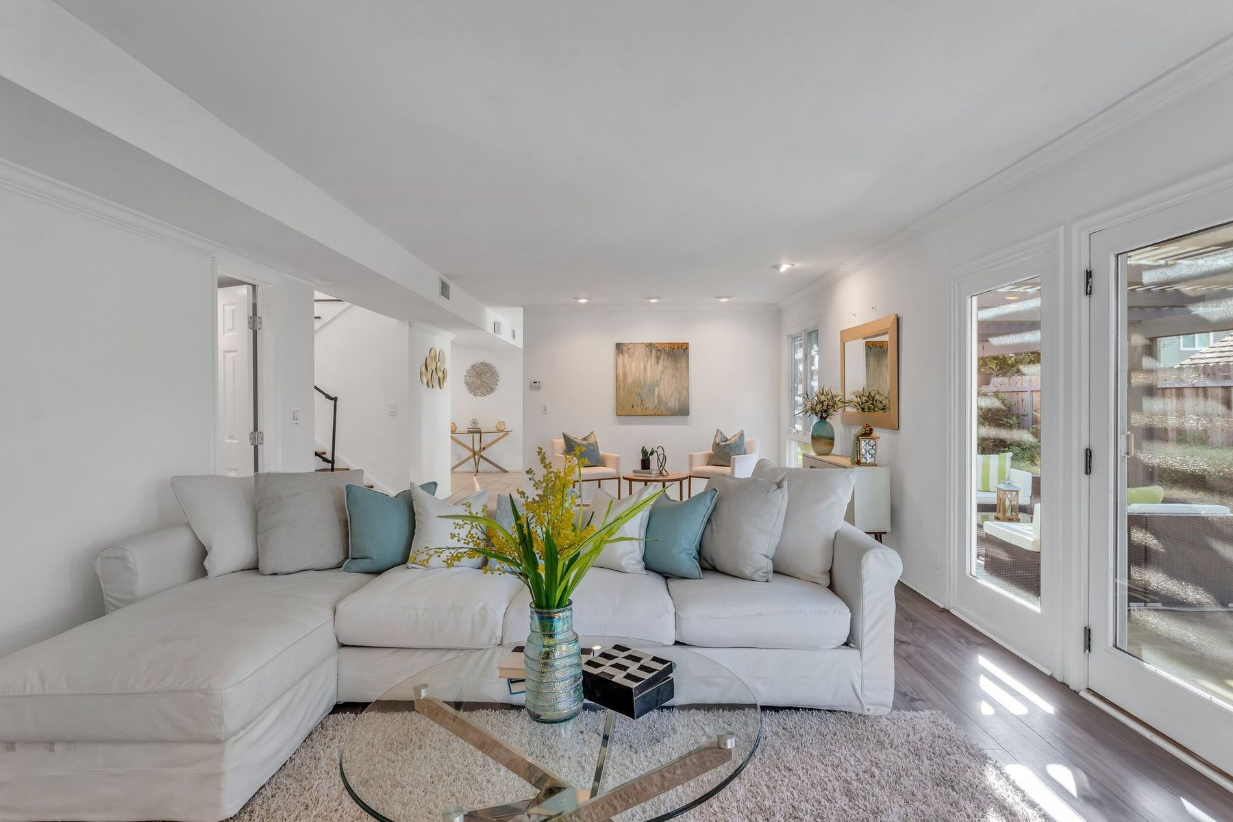 A staged family room with a white sectional and teal pillows