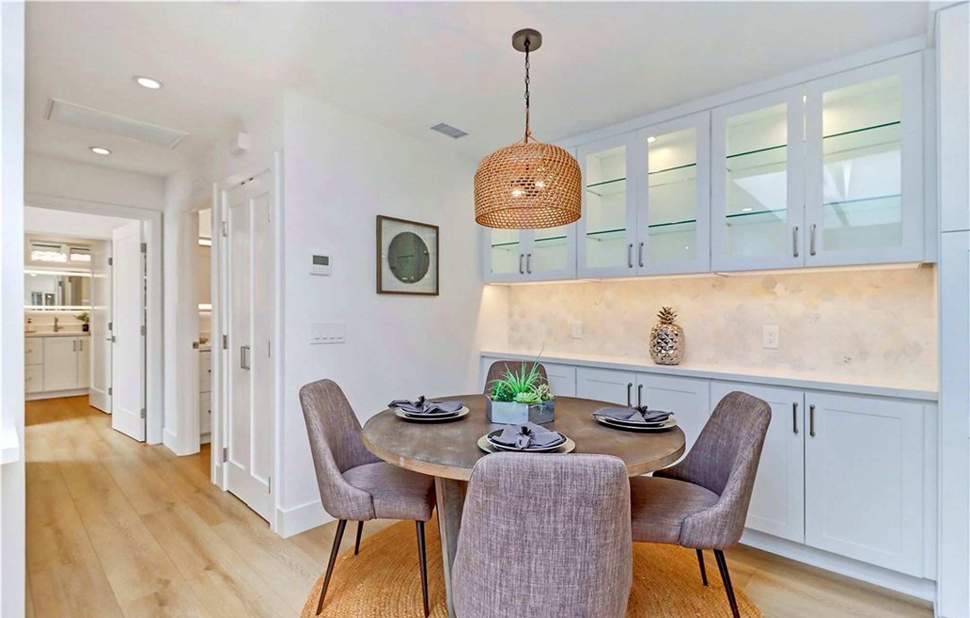 Round wood dining table with mauve chairs under a woven pendant, Laguna Woods