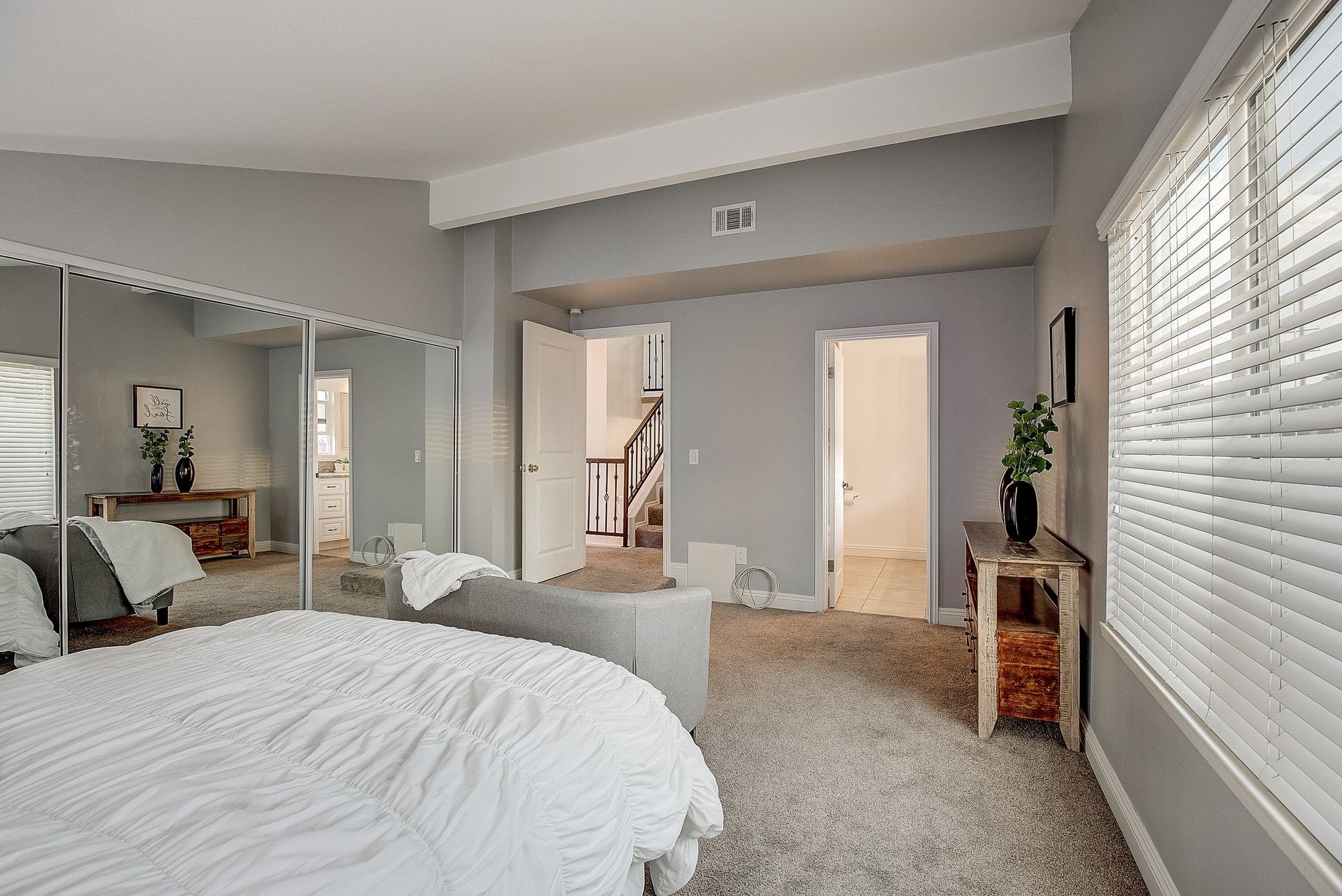 Bedroom with white bedding and mirrored closet doors, Huntington Beach