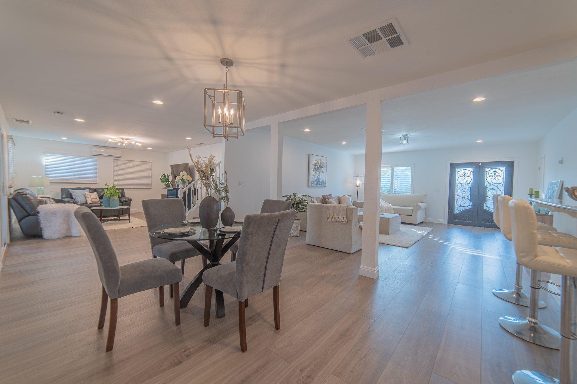 Round glass dining table with gray chairs, open to the living room, Anaheim