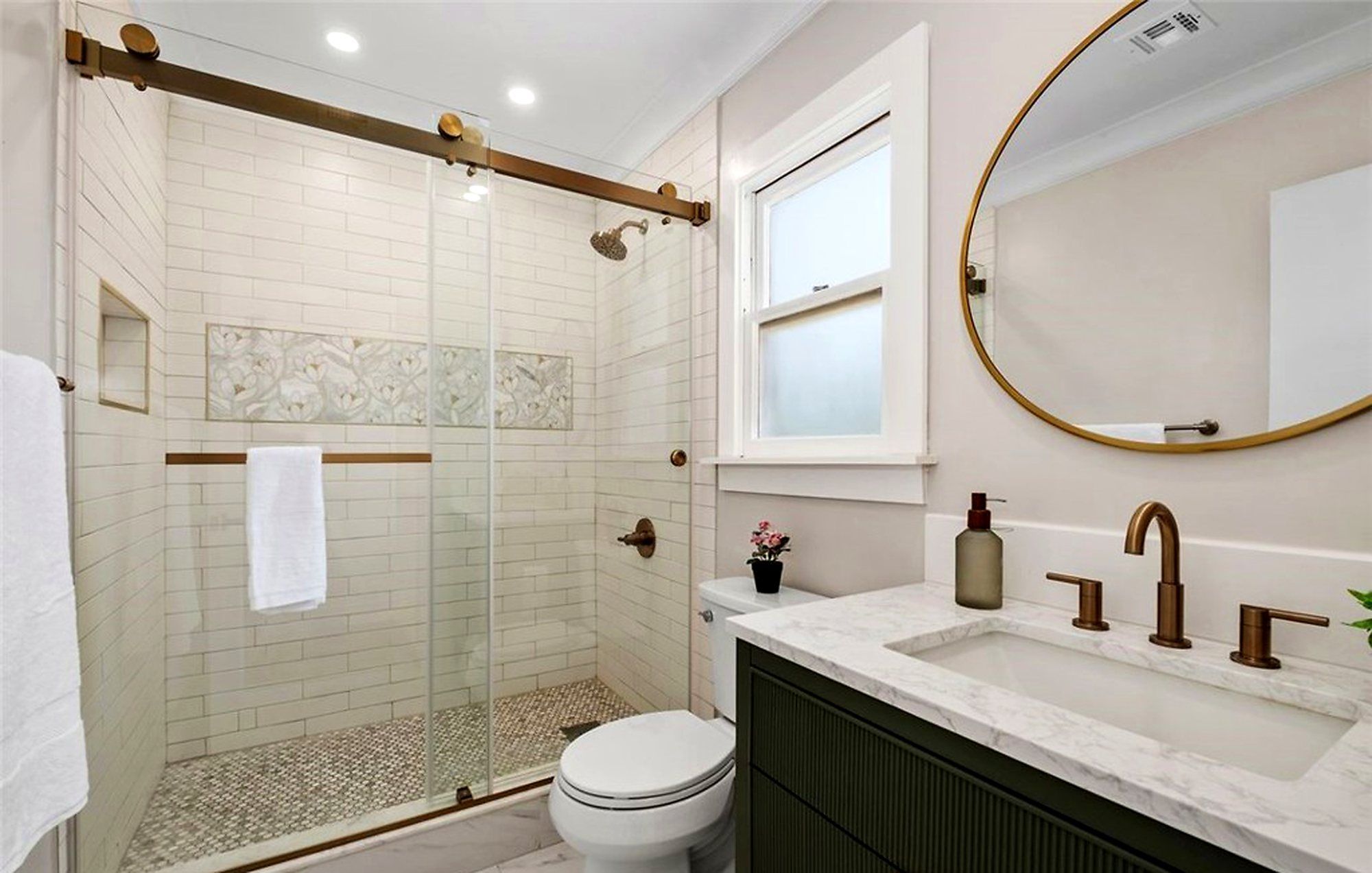 Bathroom with a sliding glass shower door and an oval brass mirror, Santa Ana