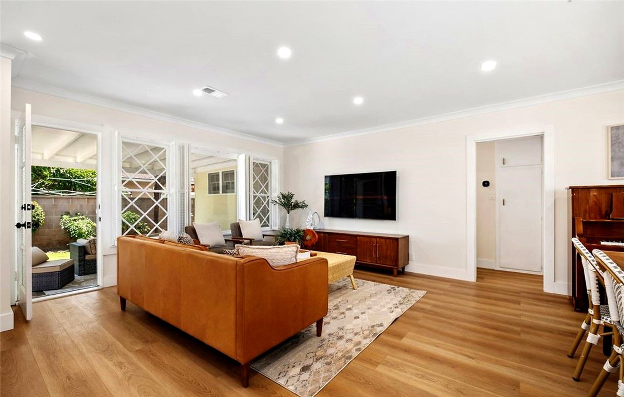 Tan leather sofa facing a media console, with diamond-pane windows behind, Santa Ana
