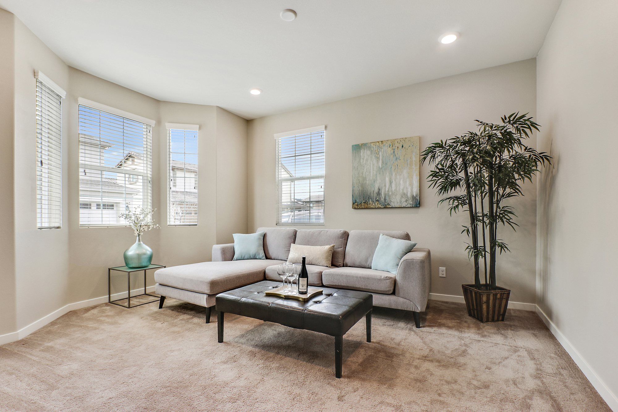 Living room with a gray sectional, a dark leather ottoman and bay windows, Irvine