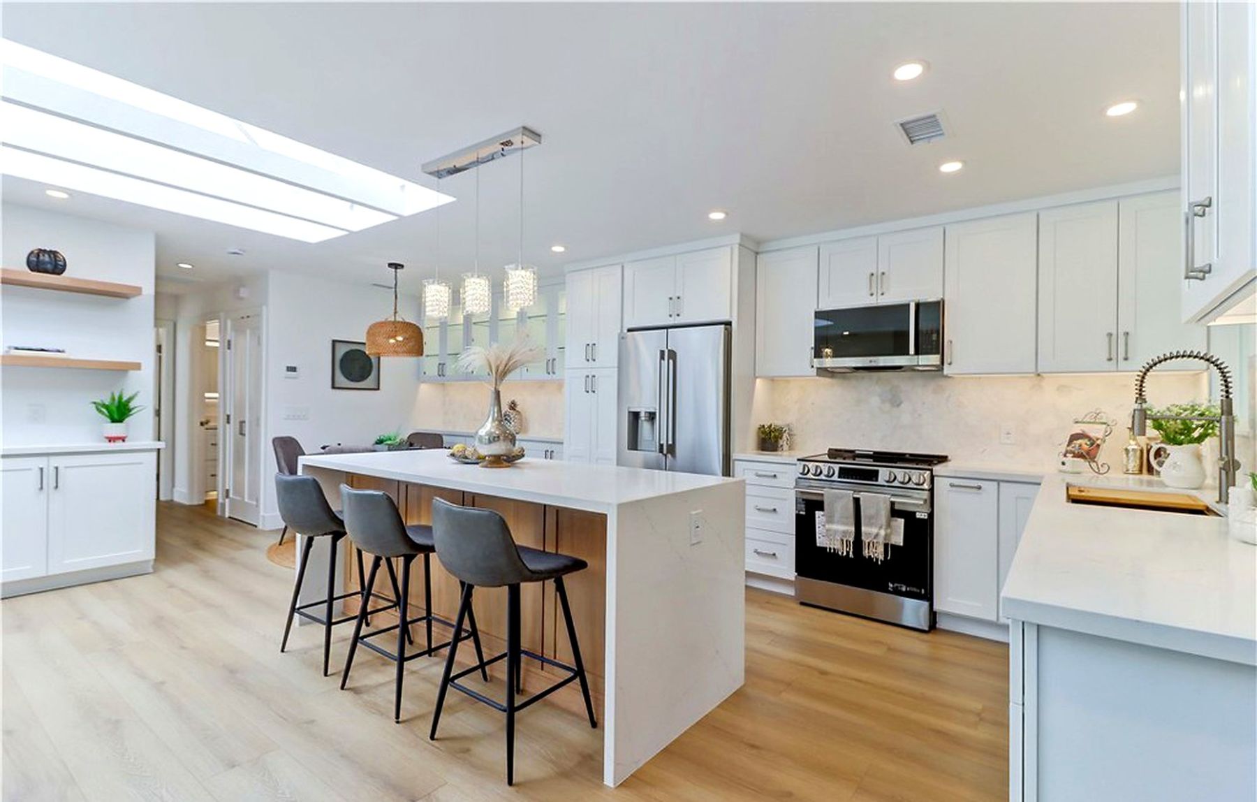 A new white kitchen staged with four gray stools at the island