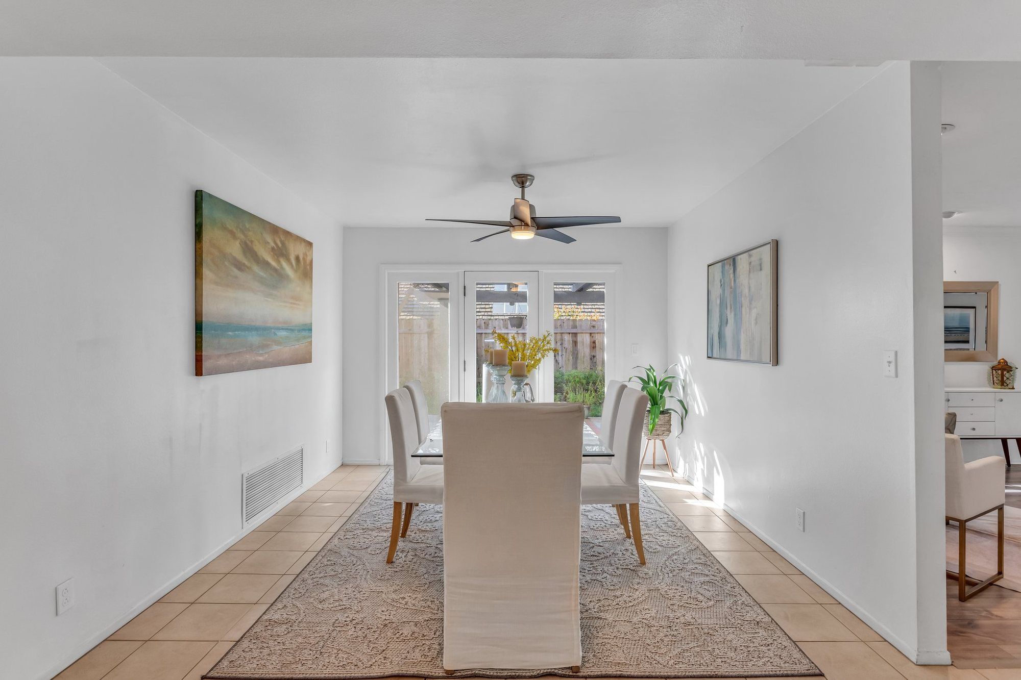 Dining room with white slipcovered chairs and coastal art, Tustin