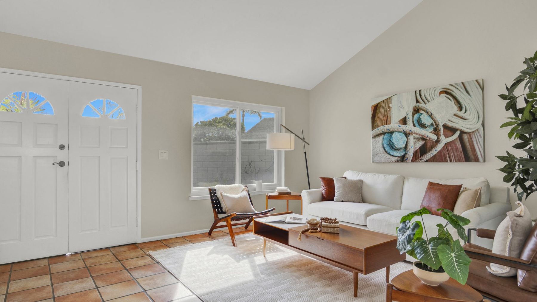 A staged living room with a white sofa, a walnut coffee table and abstract art