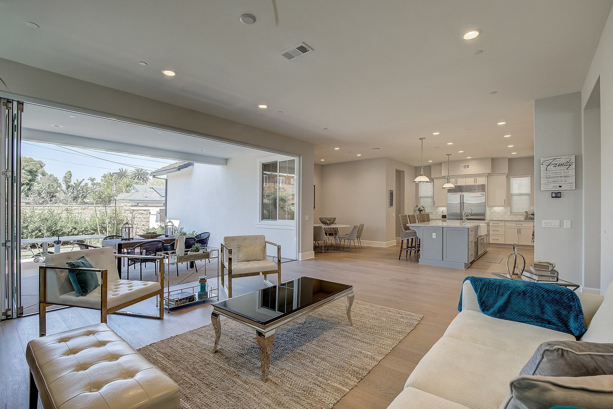 White sofa with teal throws and a tufted bench, Costa Mesa