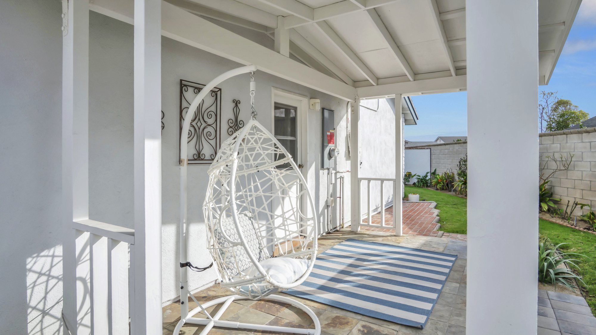 Covered porch with a hanging egg chair and a striped rug, Dana Point