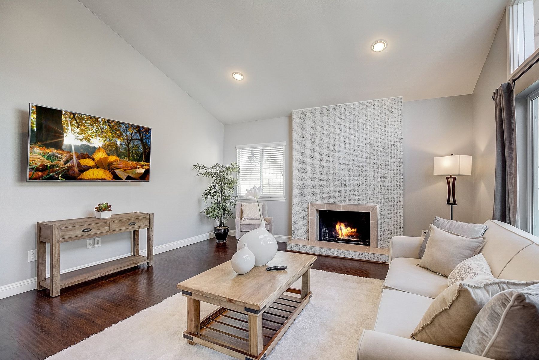 A staged living room with a stone-tile fireplace and a cream sofa