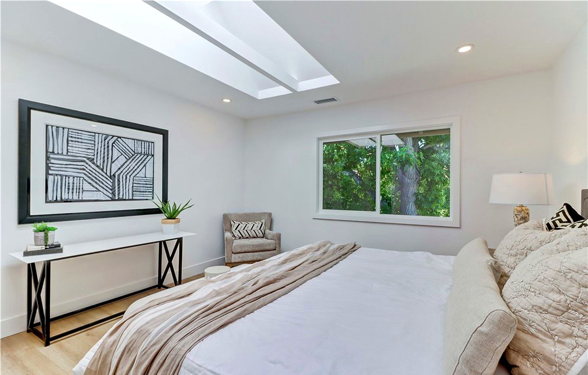 Bedroom with striped bedding, a black console and geometric art, Laguna Woods