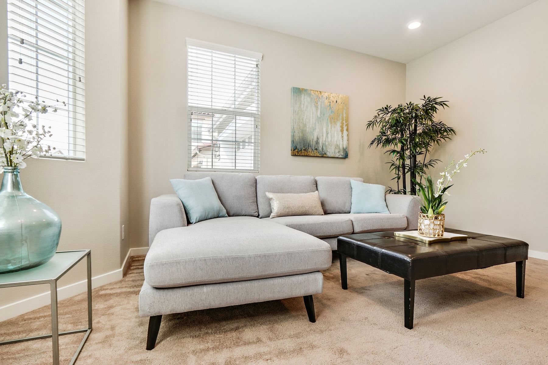 A staged living room with a gray sectional and pale blue pillows