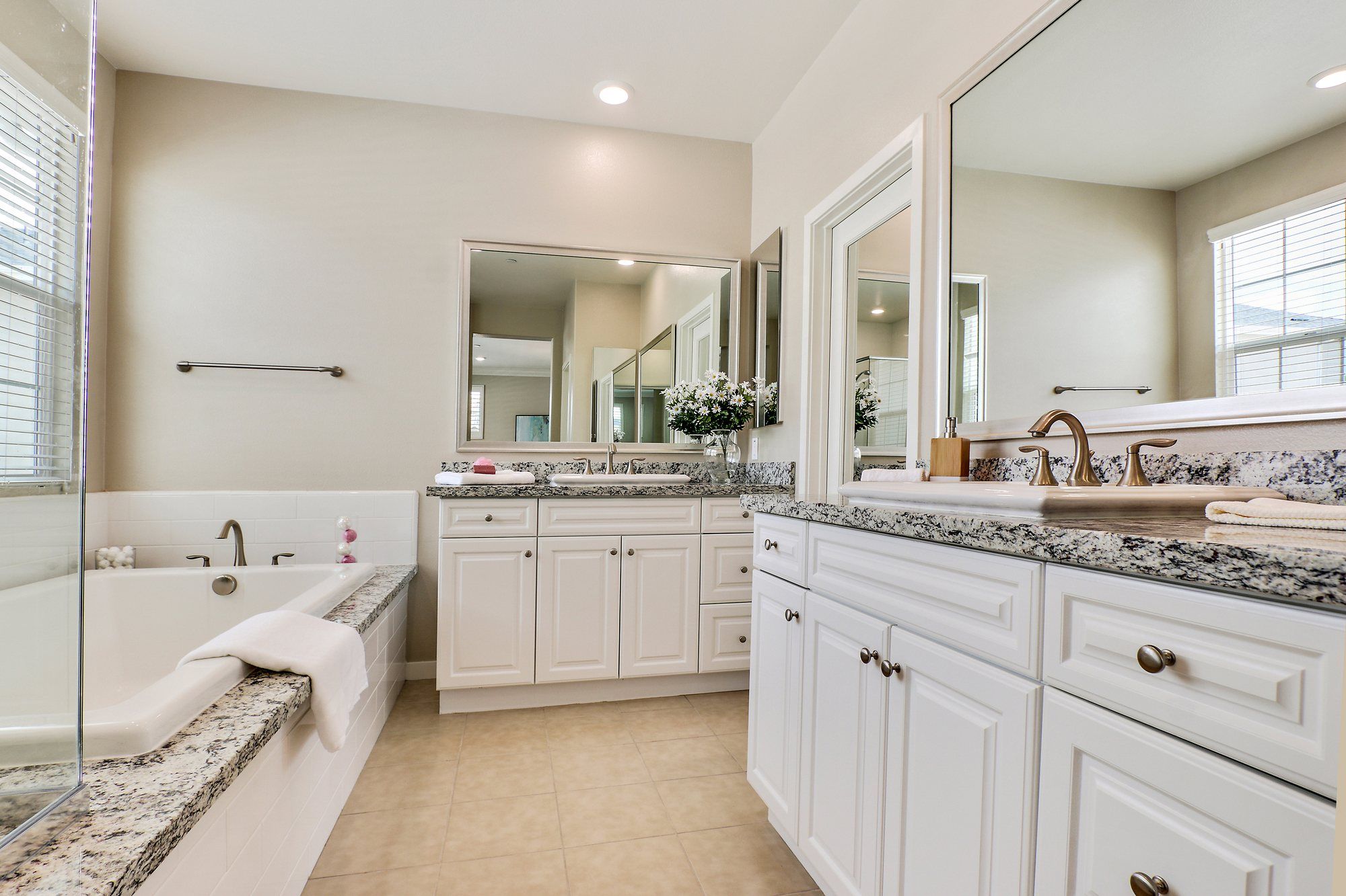 Primary bathroom with white cabinets, granite counters and a soaking tub, Irvine