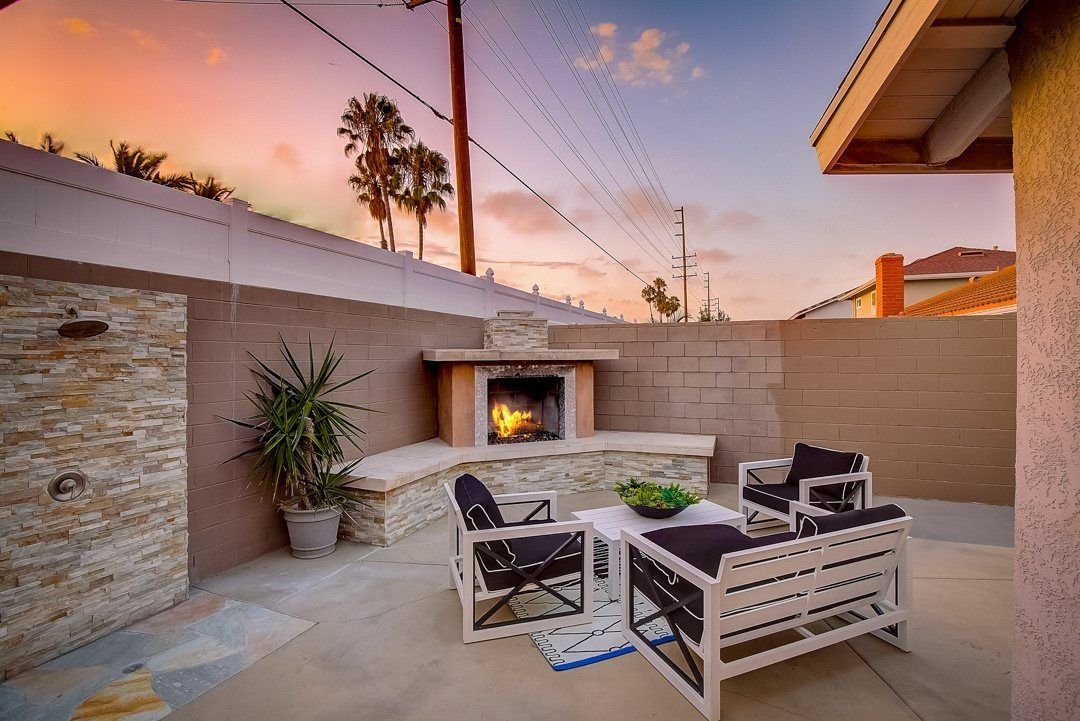 Patio with an outdoor fireplace and black-and-white chairs at sunset, Huntington Beach