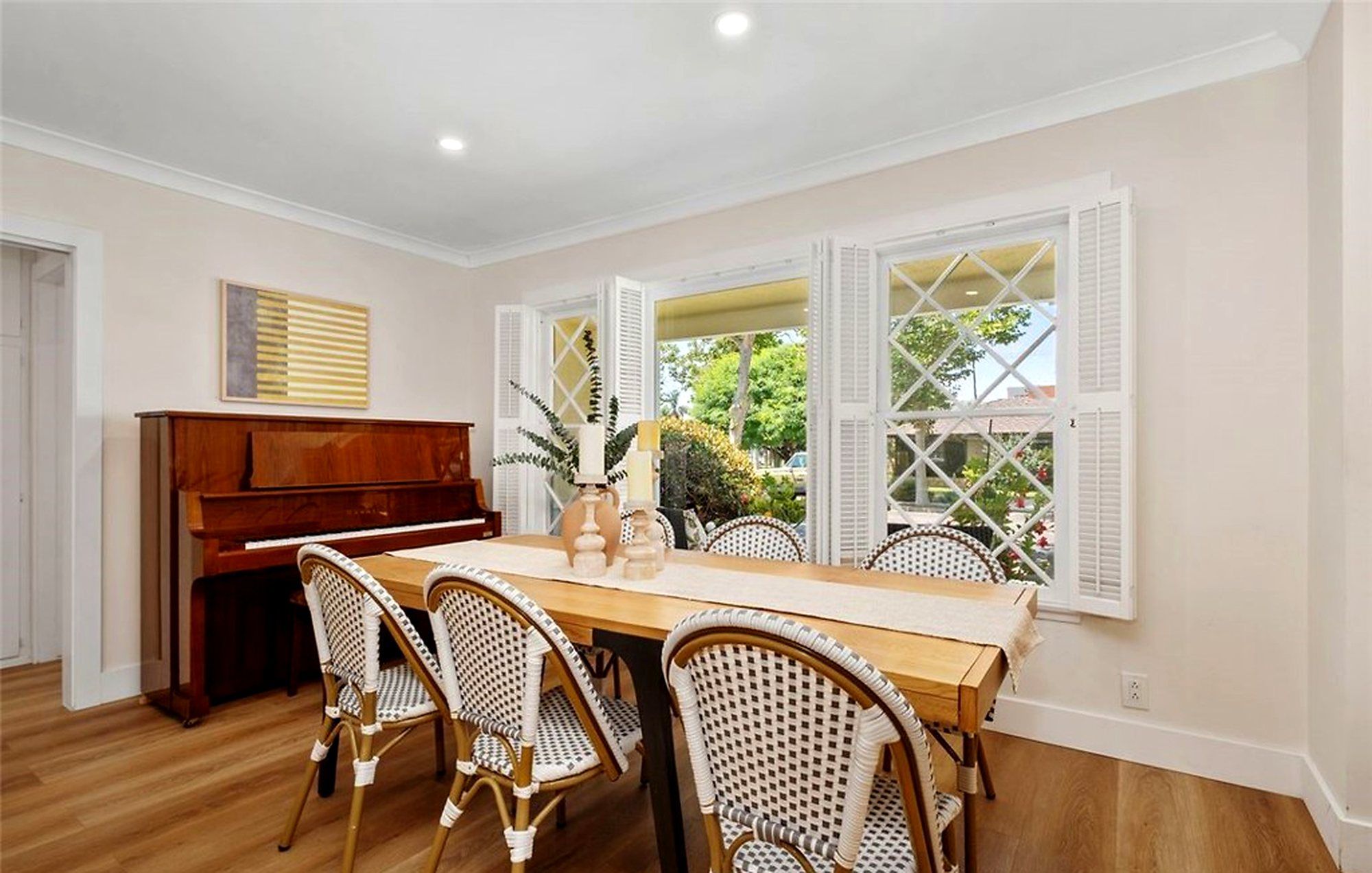 Wood dining table with rattan bistro chairs next to an upright piano, Santa Ana