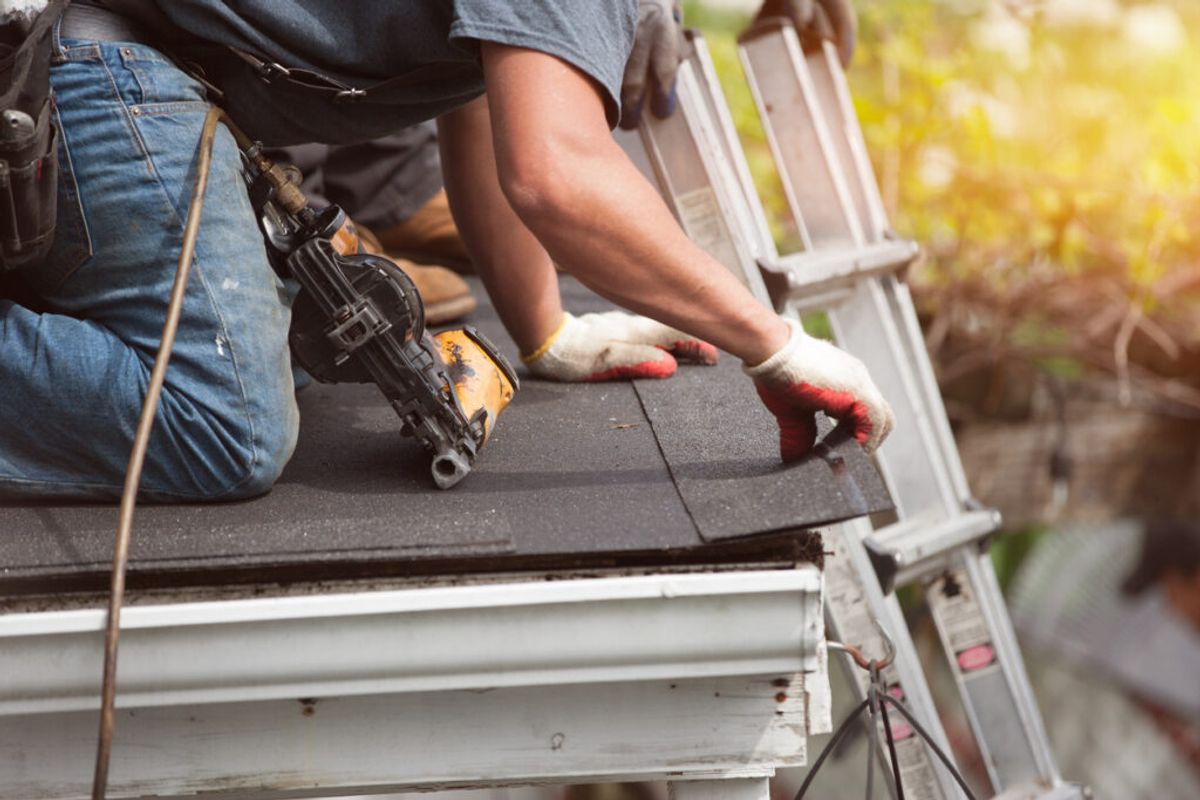 roof replacement insurance - A male roofing contractor using special tools to repair a home's roofing.