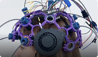 Neuronic Helmet viewed from behind, showing purple and blue light-emitting diodes arranged around a dark central hub with attached wires