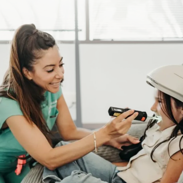 A clinician showing the Neuronic LIGHT helmet to a young client at OTEIM in California.