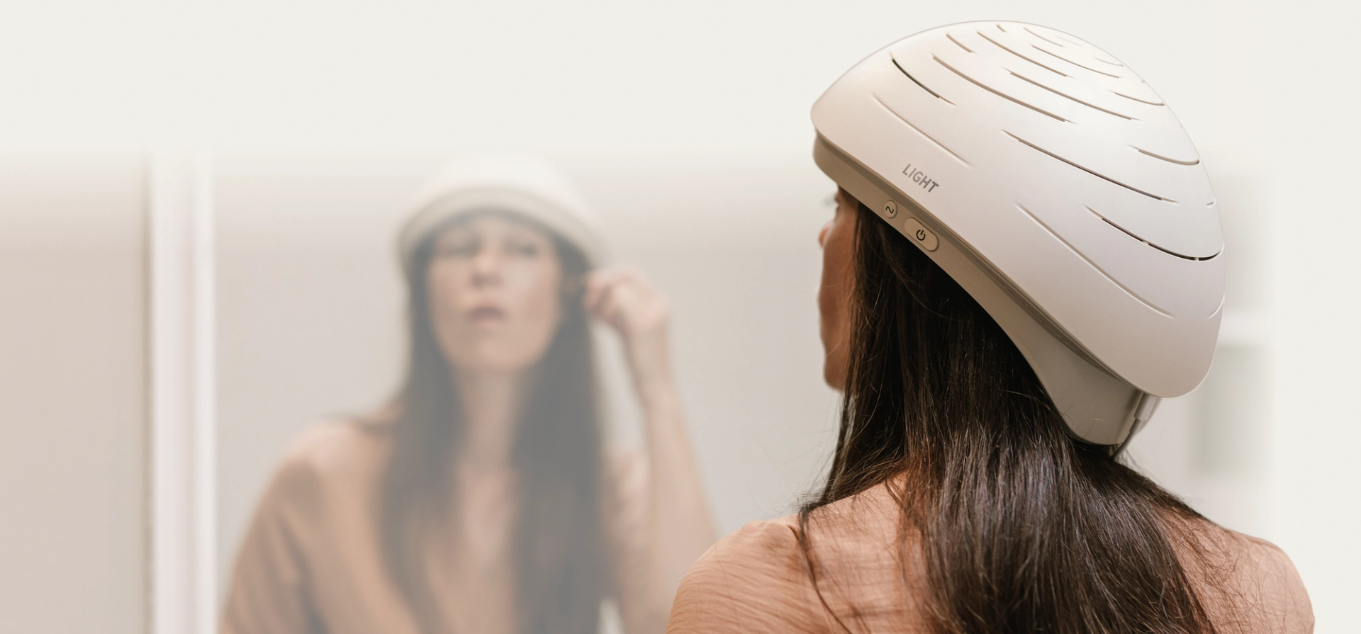 A woman wearing the Neuronic LIGHT helmet, seen from behind