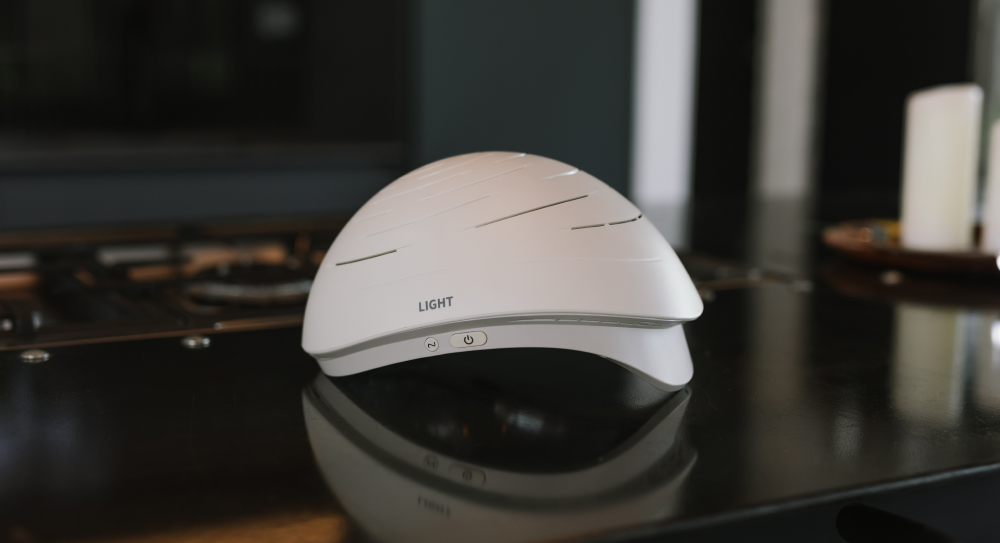 White Neuronic Helmet sitting on a black desk with control buttons and LIGHT label visible on the front