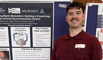 Person wearing maroon Neuronic staff shirt standing next to research poster about near-infrared neuromodulation system