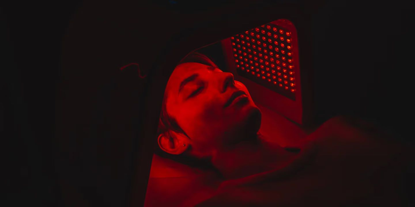 Person wearing Neuronic Helmet emitting red light, eyes closed, head tilted back