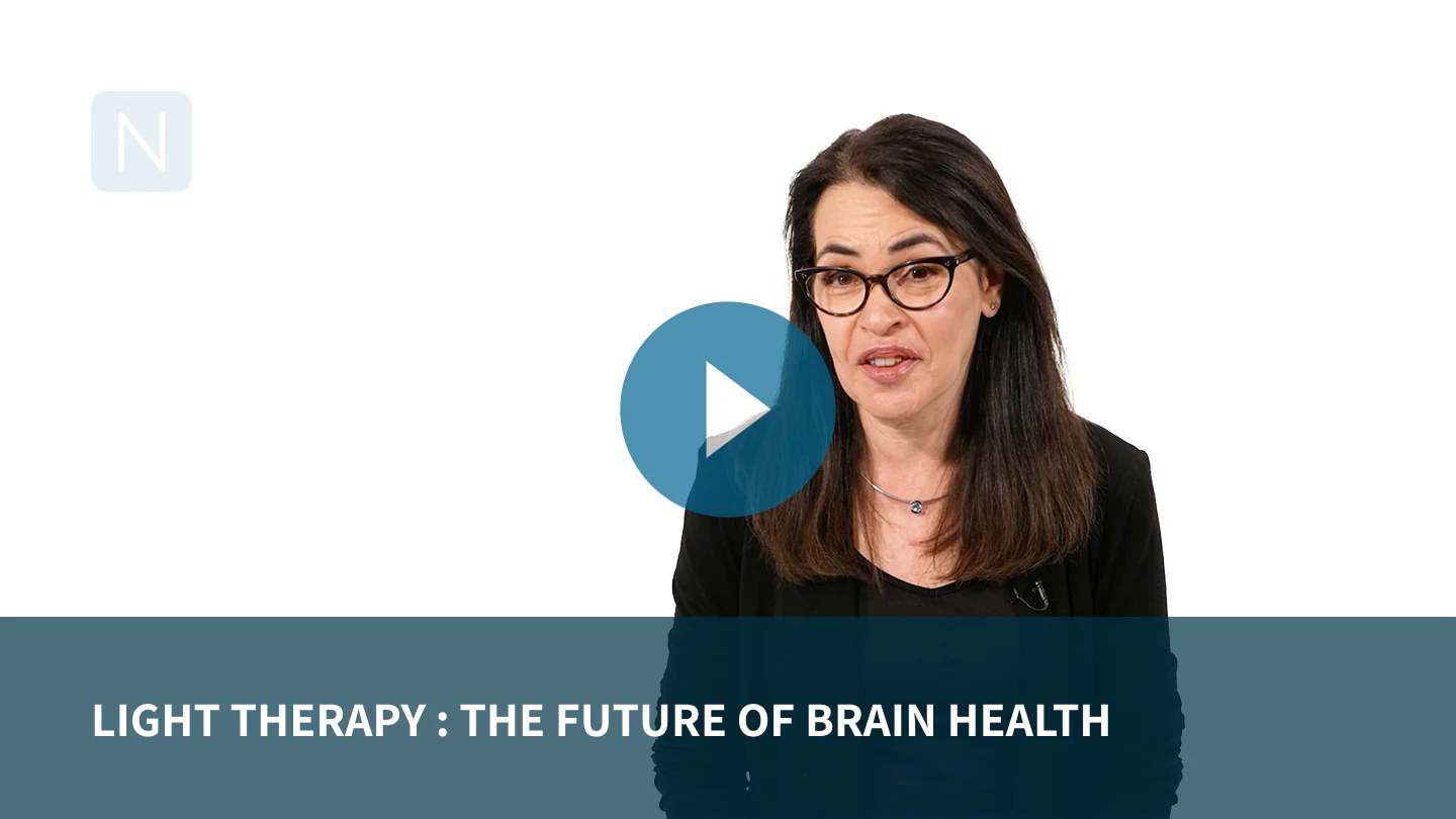 Woman wearing glasses speaking to camera with video play button overlay