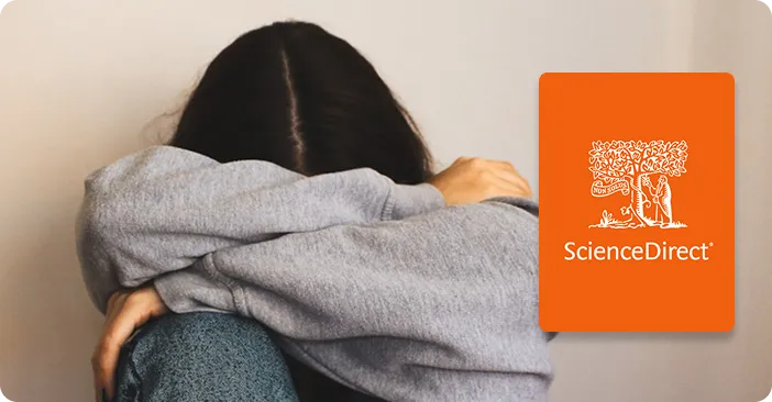 Person from behind wearing gray hoodie, holding ScienceDirect book with orange cover