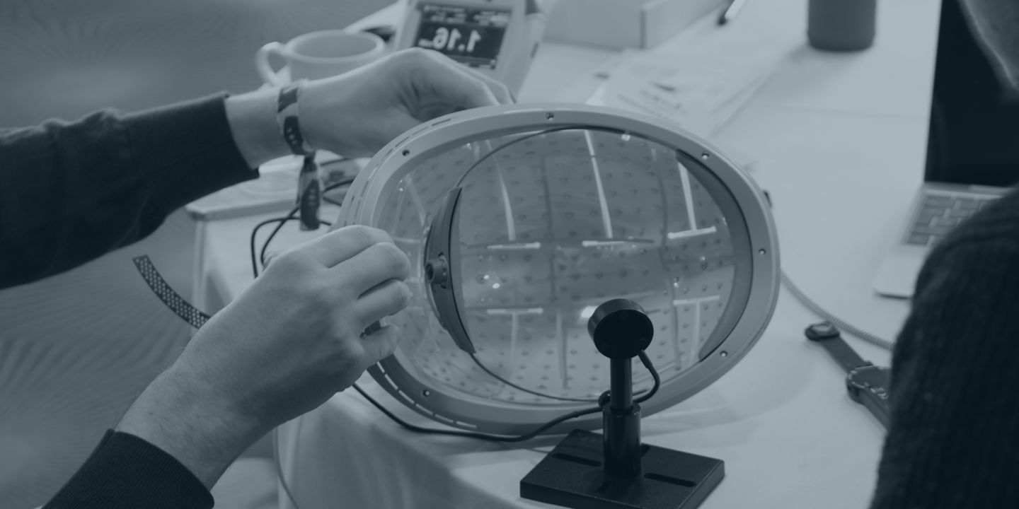 Hands holding a circular light-therapy helmet component showing internal LED array grid pattern during product demonstration