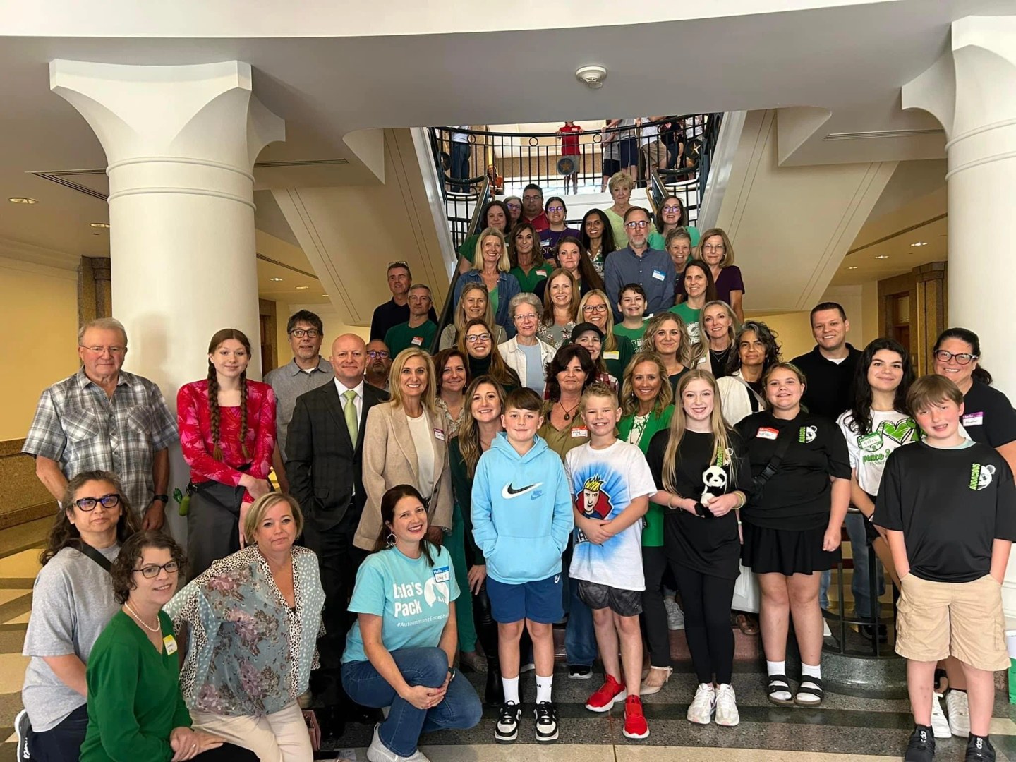 Large group of adults and children standing together on a staircase inside a building