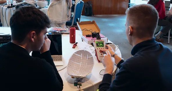Two people at a table examining a Neuronic Helmet with visible light-emitting components