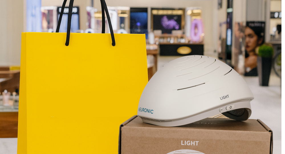 Neuronic Helmet sitting on cardboard box labeled LIGHT, next to yellow shopping bag with black handles, in retail environment