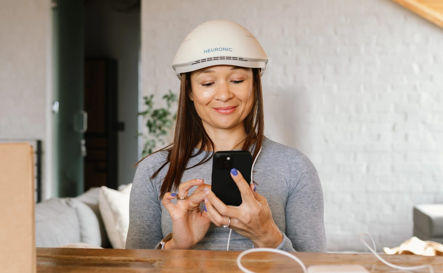 Woman wearing the Neuronic LIGHT at her desk, glancing at her phone while a short session runs