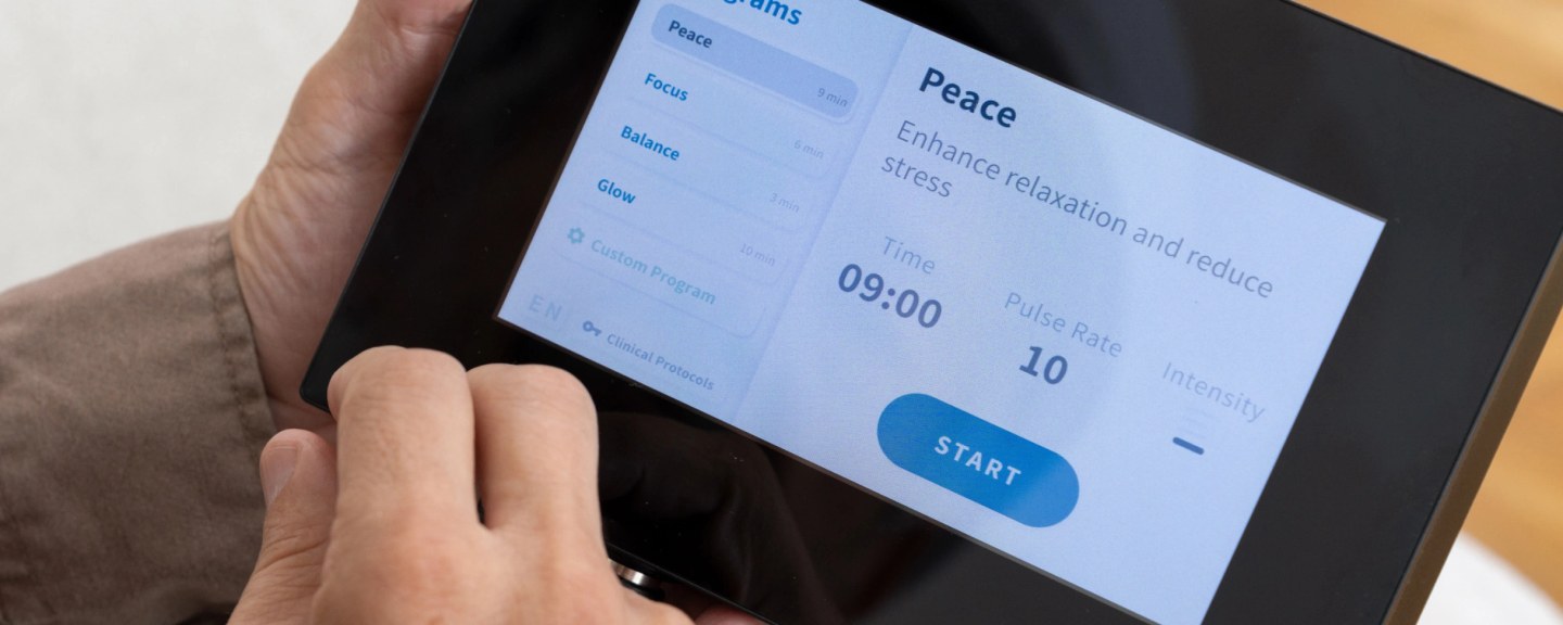 Hand holding tablet displaying Neuronic app with Peace program selected, showing 9-minute session details and START button
