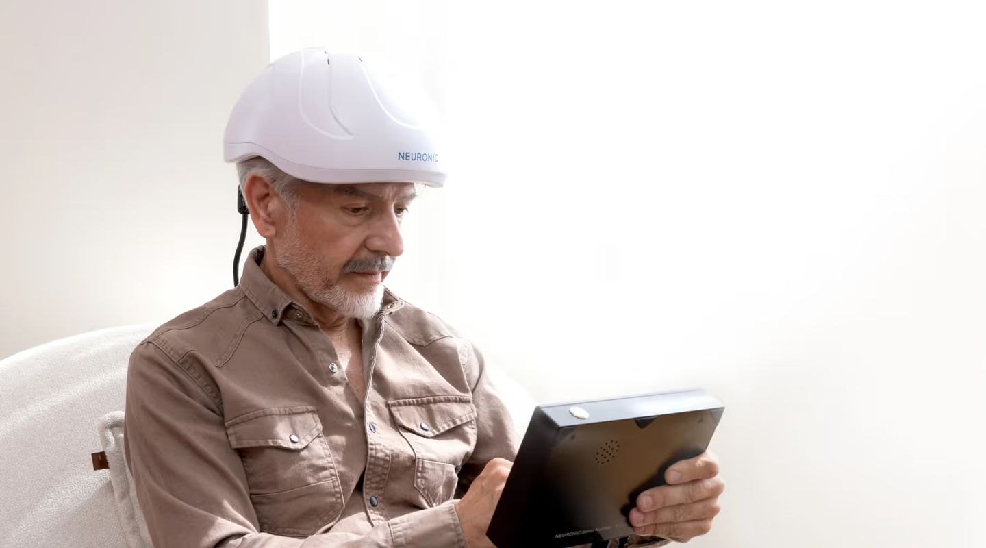 Man wearing Neuronic Helmet, looking down at tablet device
