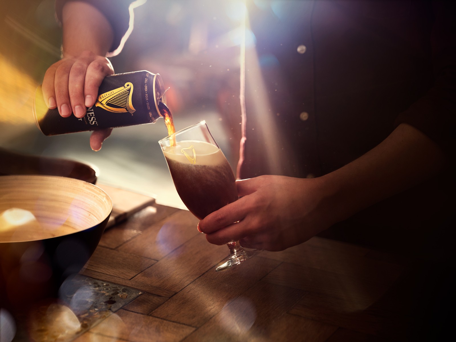 Hand pouring a pint of Guinness in kitchen, photographed by Jason Bailey Studio.