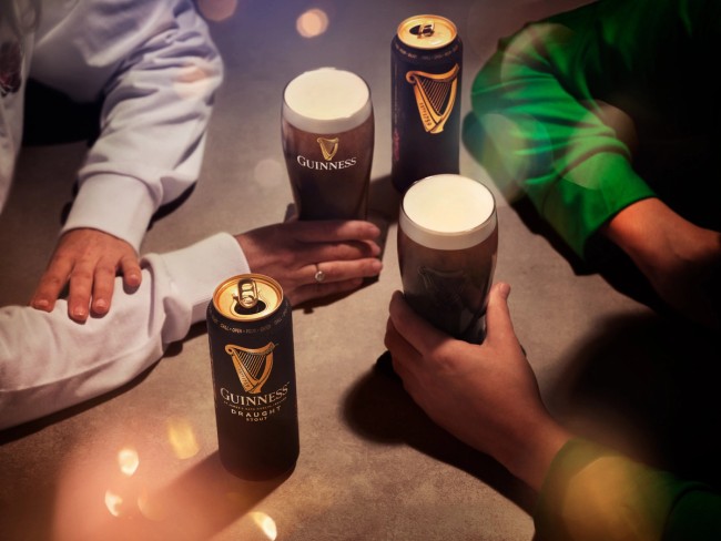 Two friends holding pints of Guinness at a table, photographed by Jason Bailey Studio.