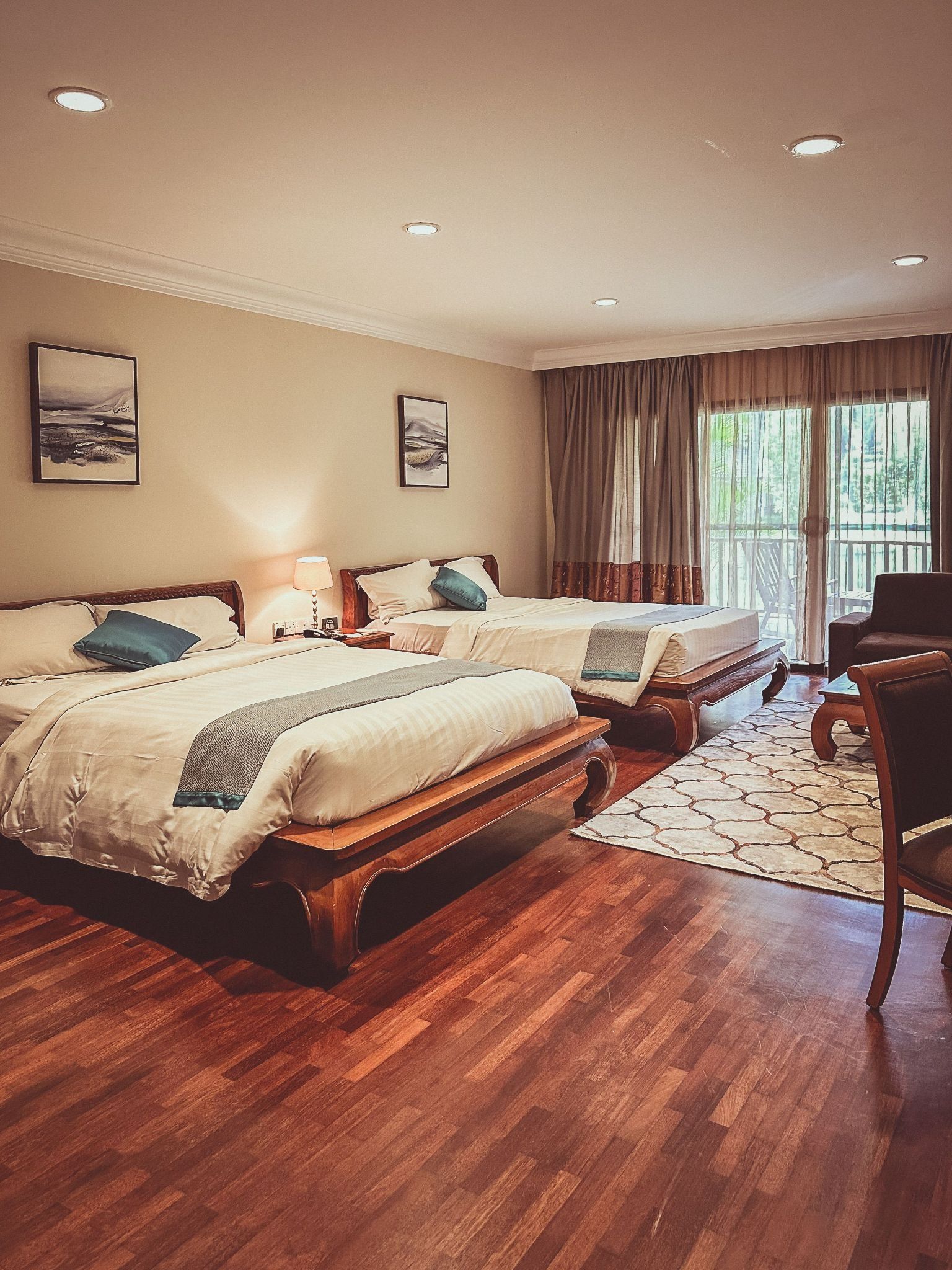 A bedroom with two wooden double beds, hardwood floors, and sliding glass doors leading to a balcony.