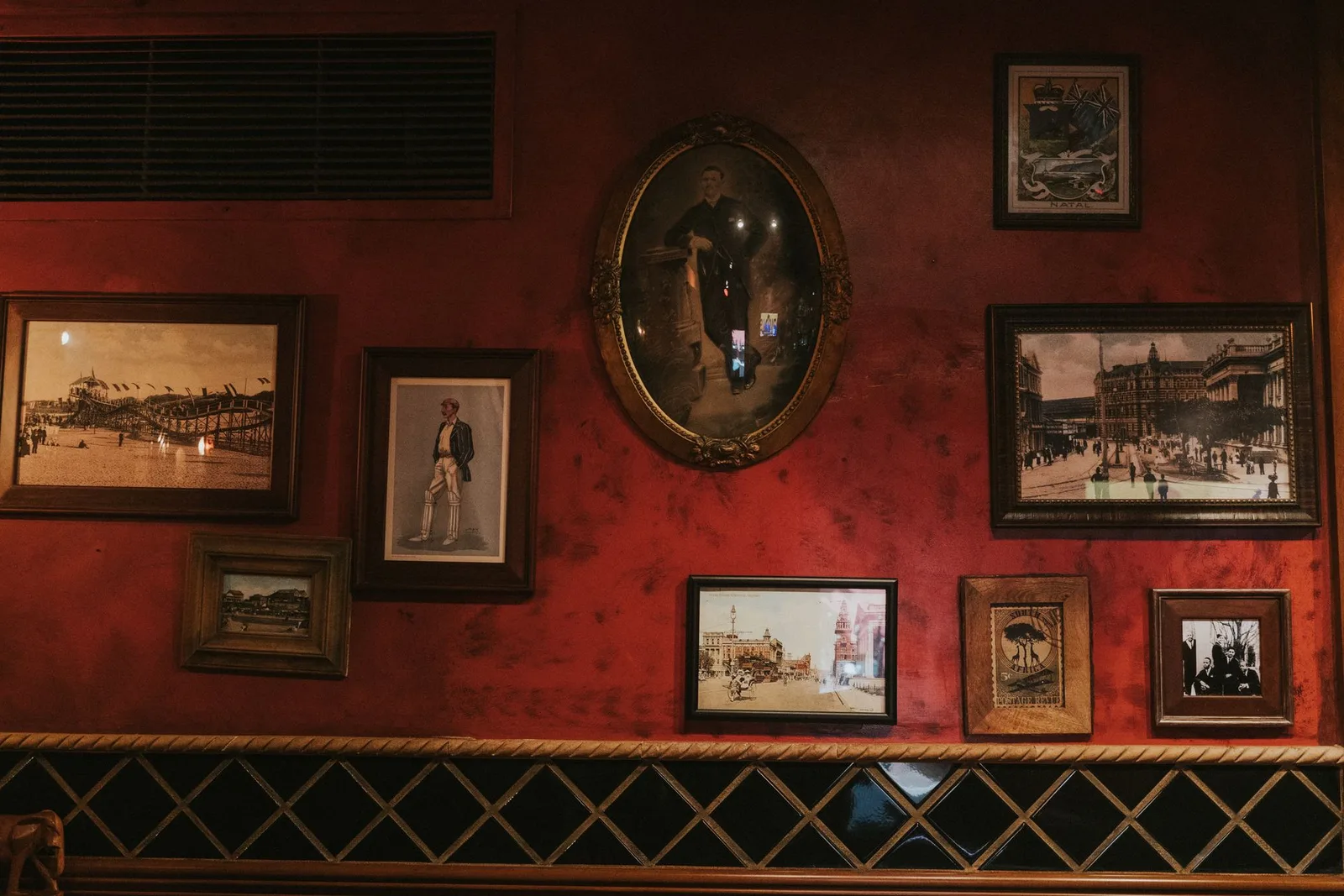 Framed vintage photographs on the Durban Room's red walls