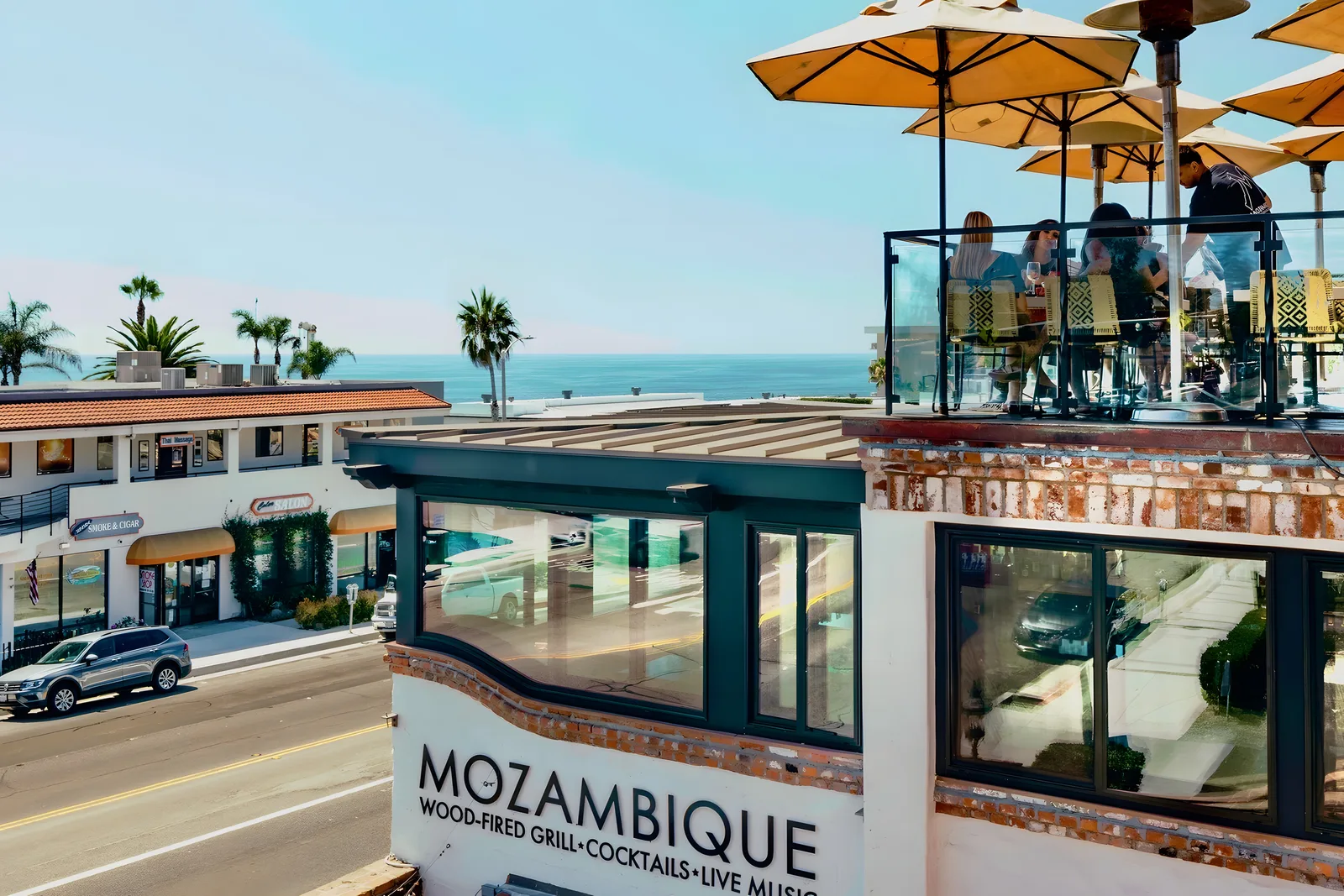 Mozambique’s exterior sign on the coast road with ocean-view rooftop diners