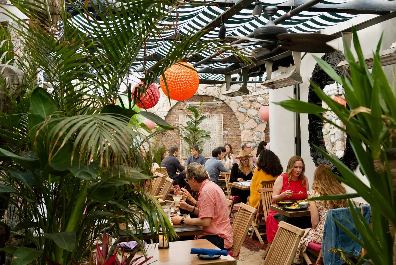 Guests dining on the Garden Patio among palms and lanterns