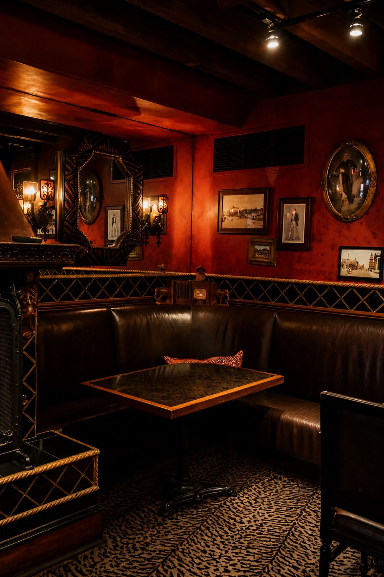 Leather corner booth in the Durban Room with framed art on red walls