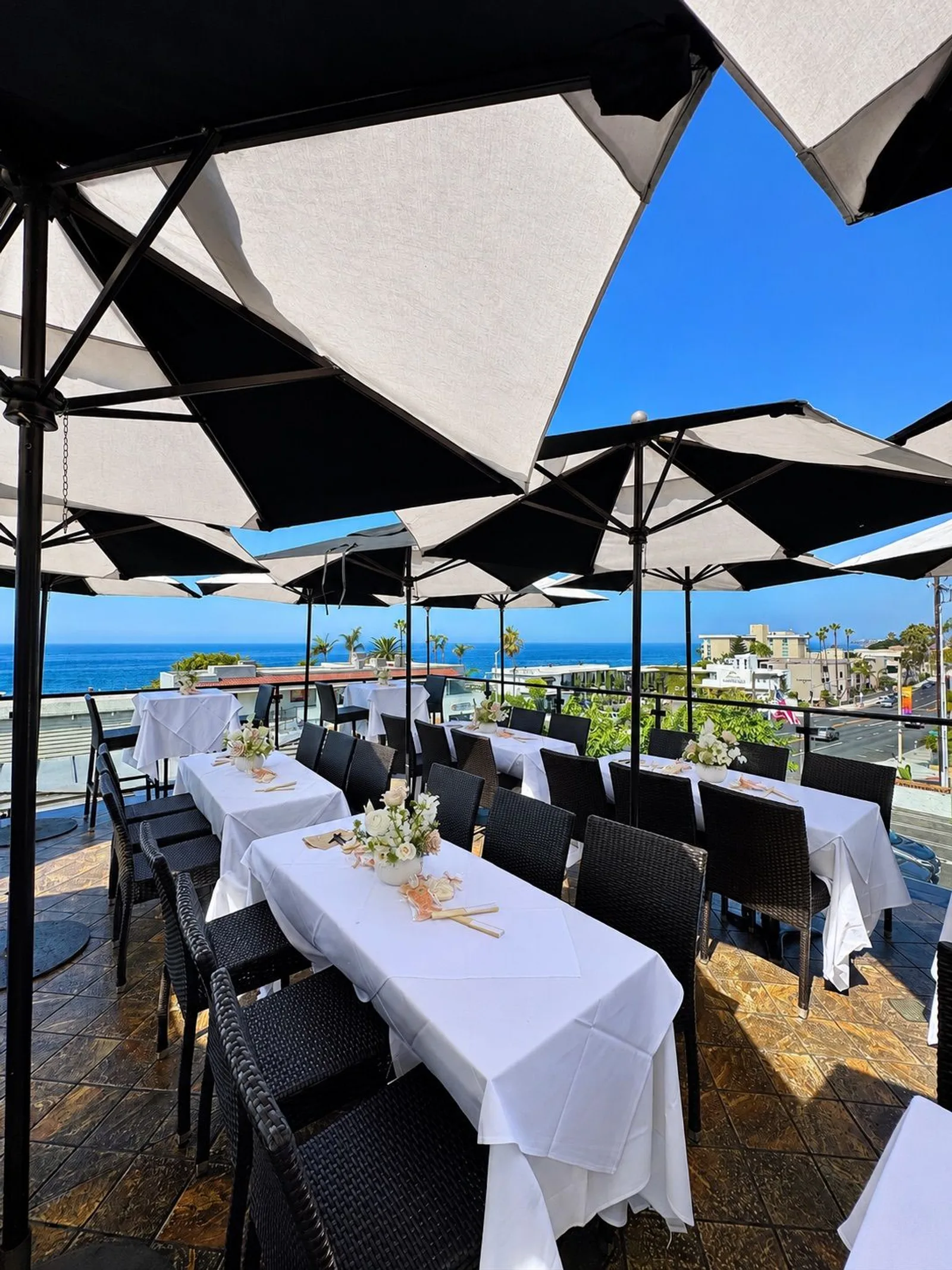Veranda Rooftop set with white-linen tables under umbrellas for an event