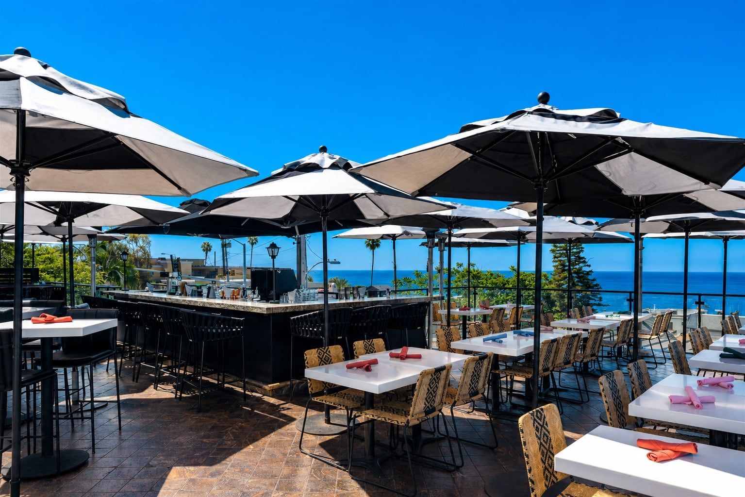 The Veranda Rooftop bar and tables under white umbrellas with an ocean view