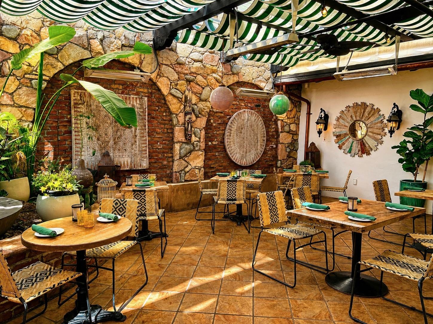 Garden Patio tables under striped awnings beside stone walls and plants