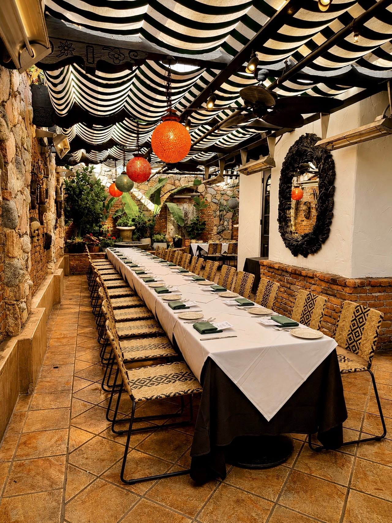 Garden Patio long table set for a private event under striped awnings