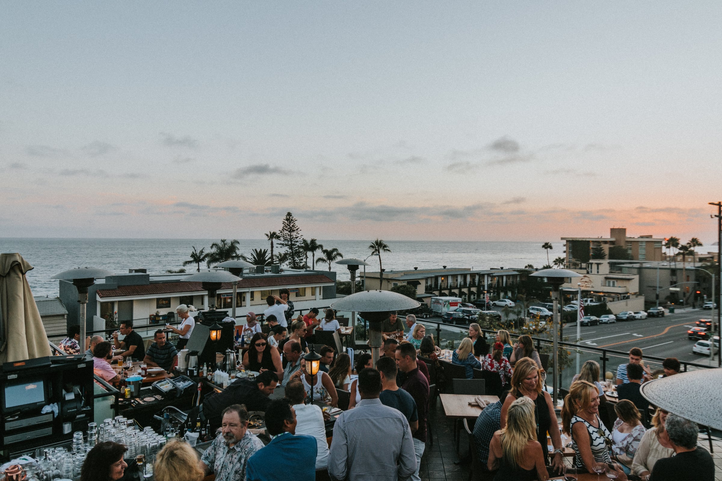 Aerial view of guests dining on Mozambique's rooftop at sunset with the ocean beyond