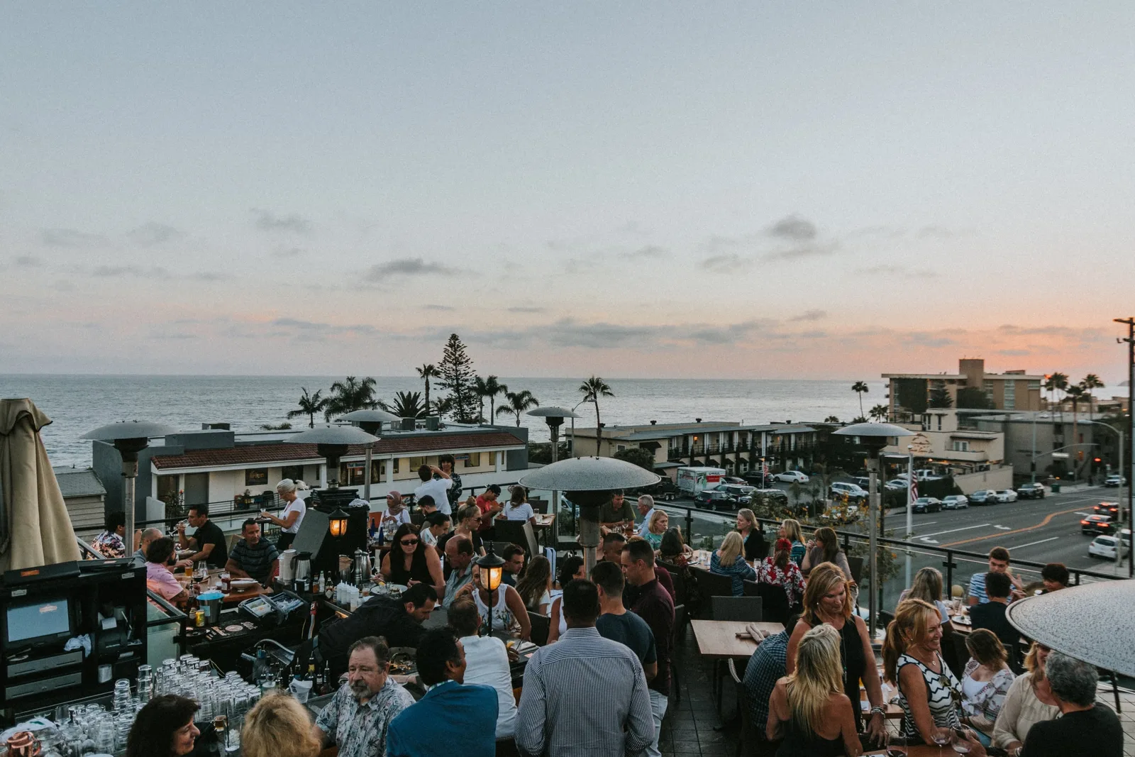 Aerial view of guests dining on Mozambique's rooftop at sunset with the ocean beyond