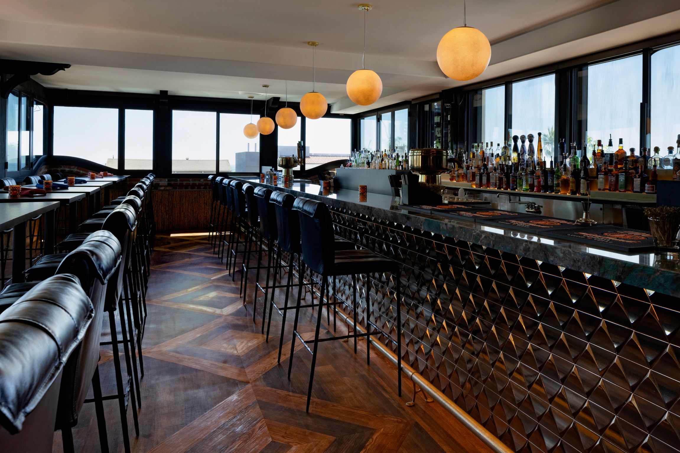 Long bar with globe pendant lights, leather stools and window walls