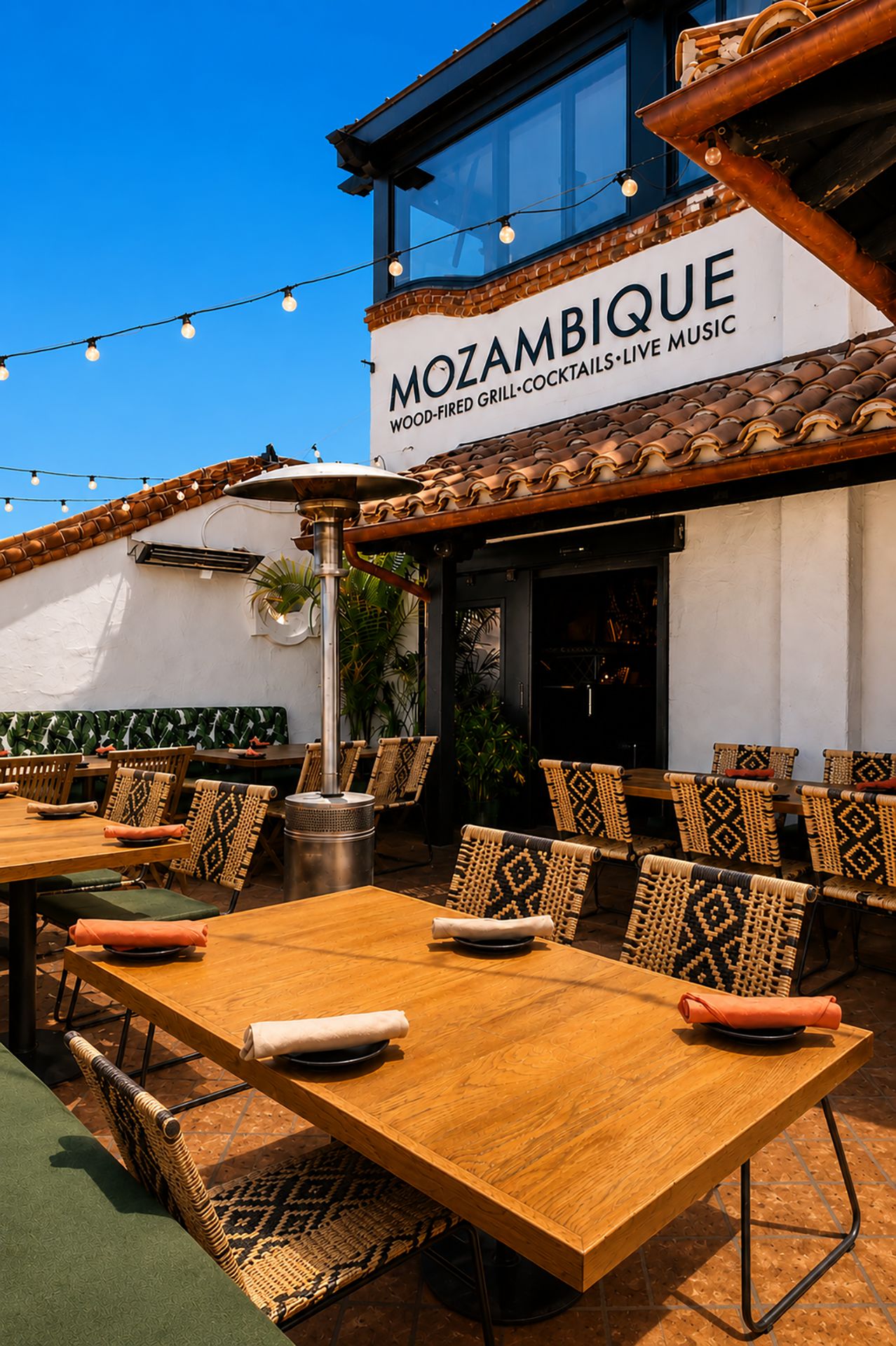 Palm Patio tables under string lights beside the Mozambique sign