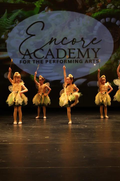 Dancers perform on stage in yellow costumes